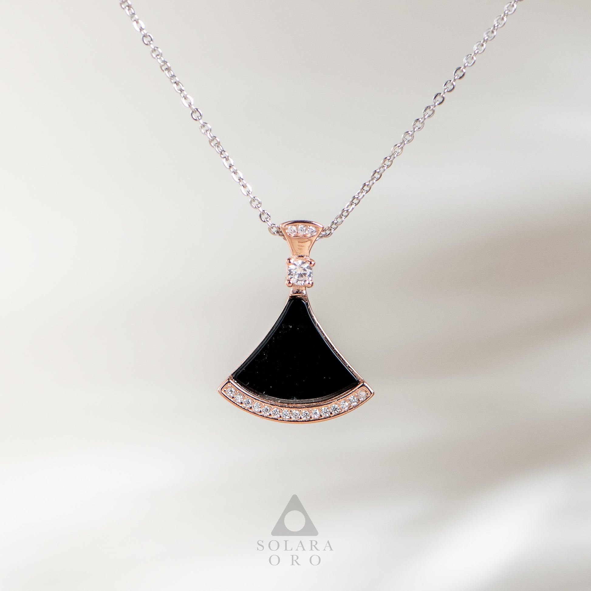 Necklace with a black pendant and rose gold accents on a light background