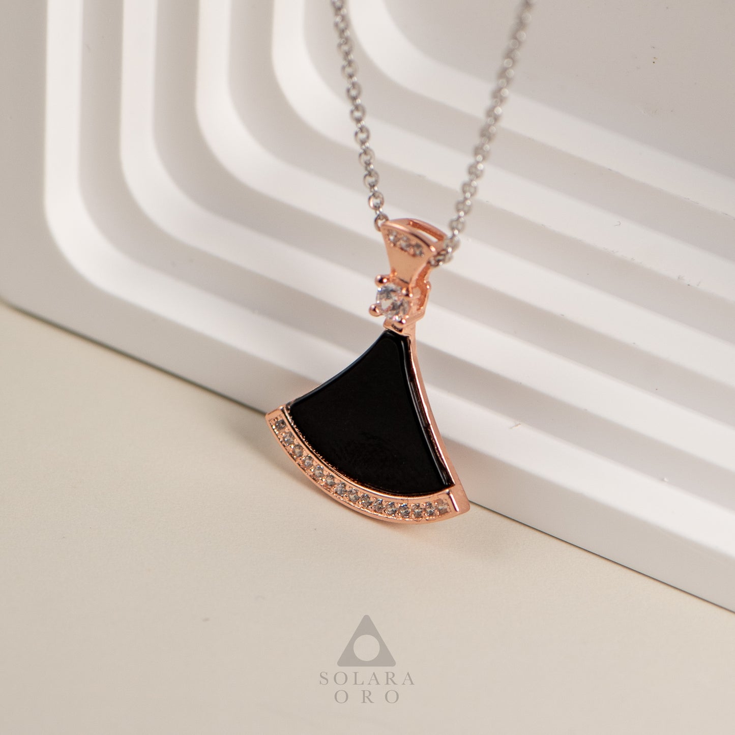 Rose gold necklace with a black pendant on a light background