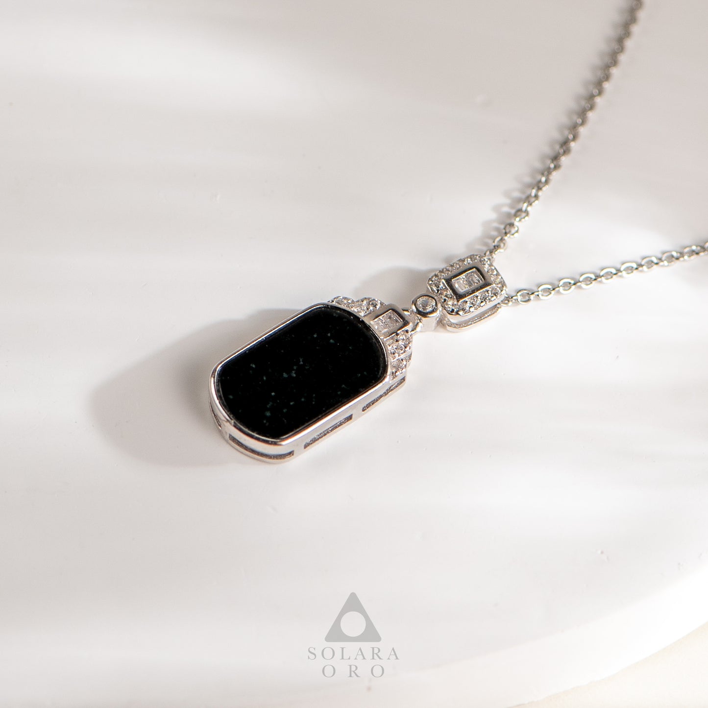 Necklace with a black pendant on a white background, featuring the Solara Oro brand.