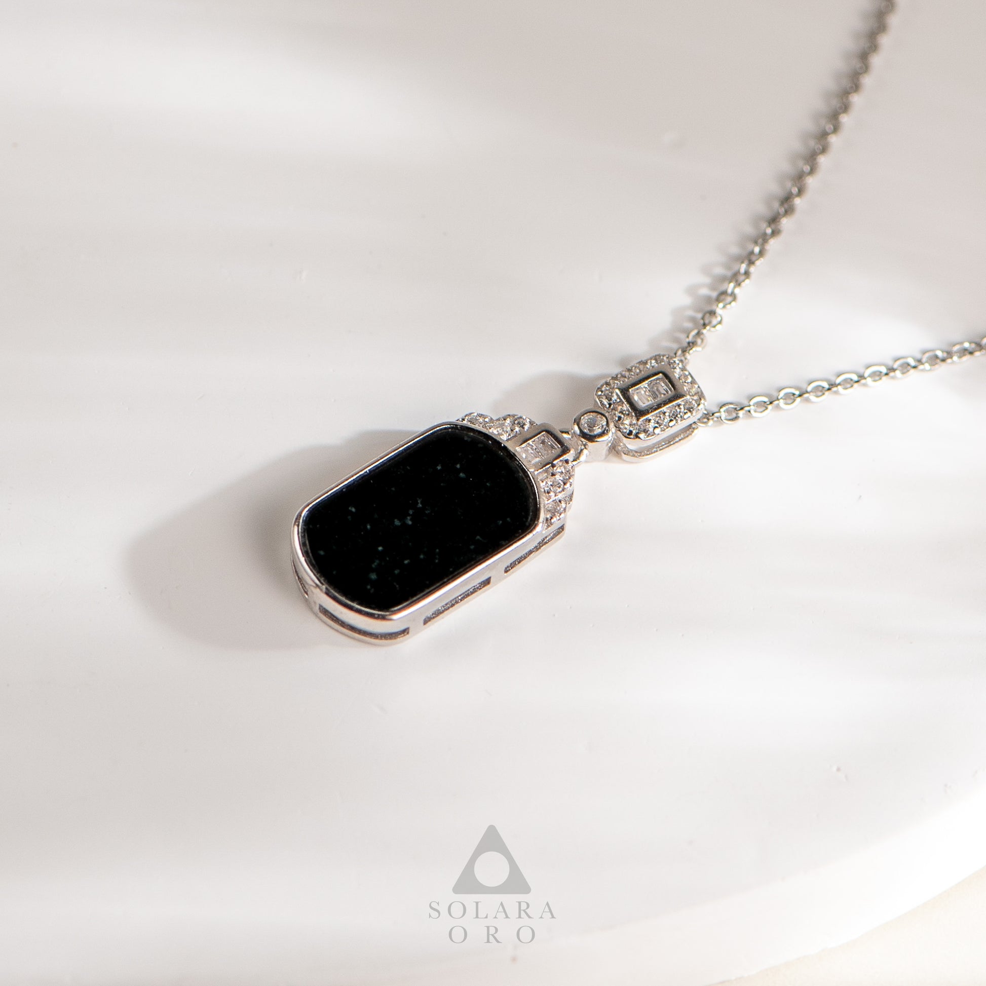 Necklace with a black pendant on a white background, featuring the Solara Oro brand.