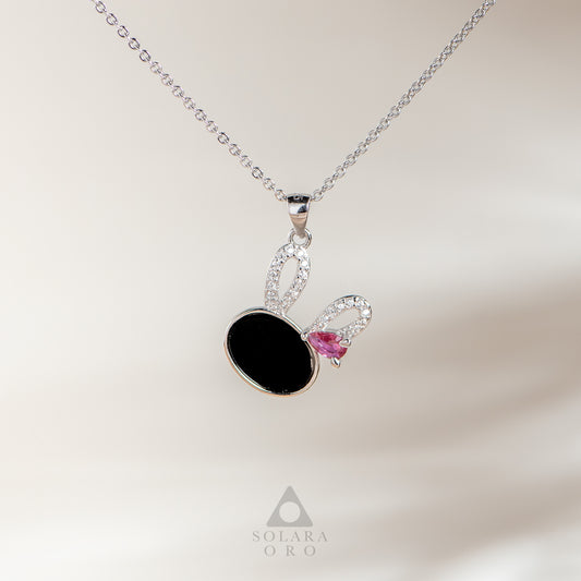 Necklace with a black pendant and pink gemstone on a light background, featuring the Solara Oro brand.