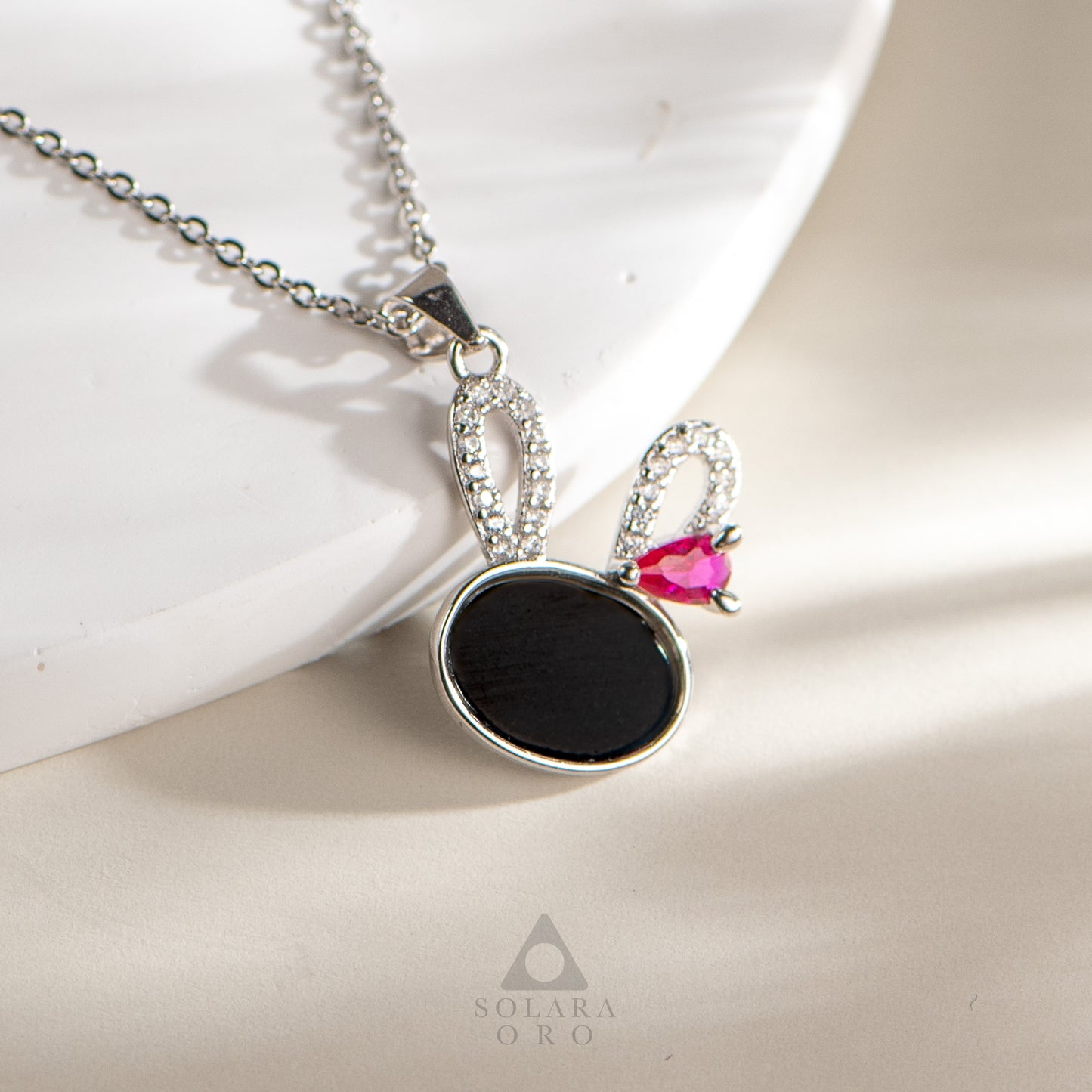 Necklace with a black pendant and pink gemstone on a light background