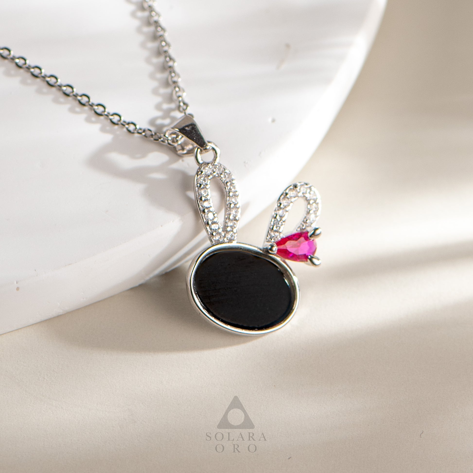 Necklace with a black pendant and pink gemstone on a light background