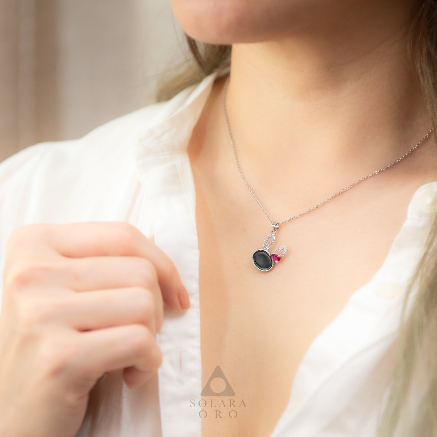 Necklace with a pendant worn by a person, brand 'Solara Oro' visible.