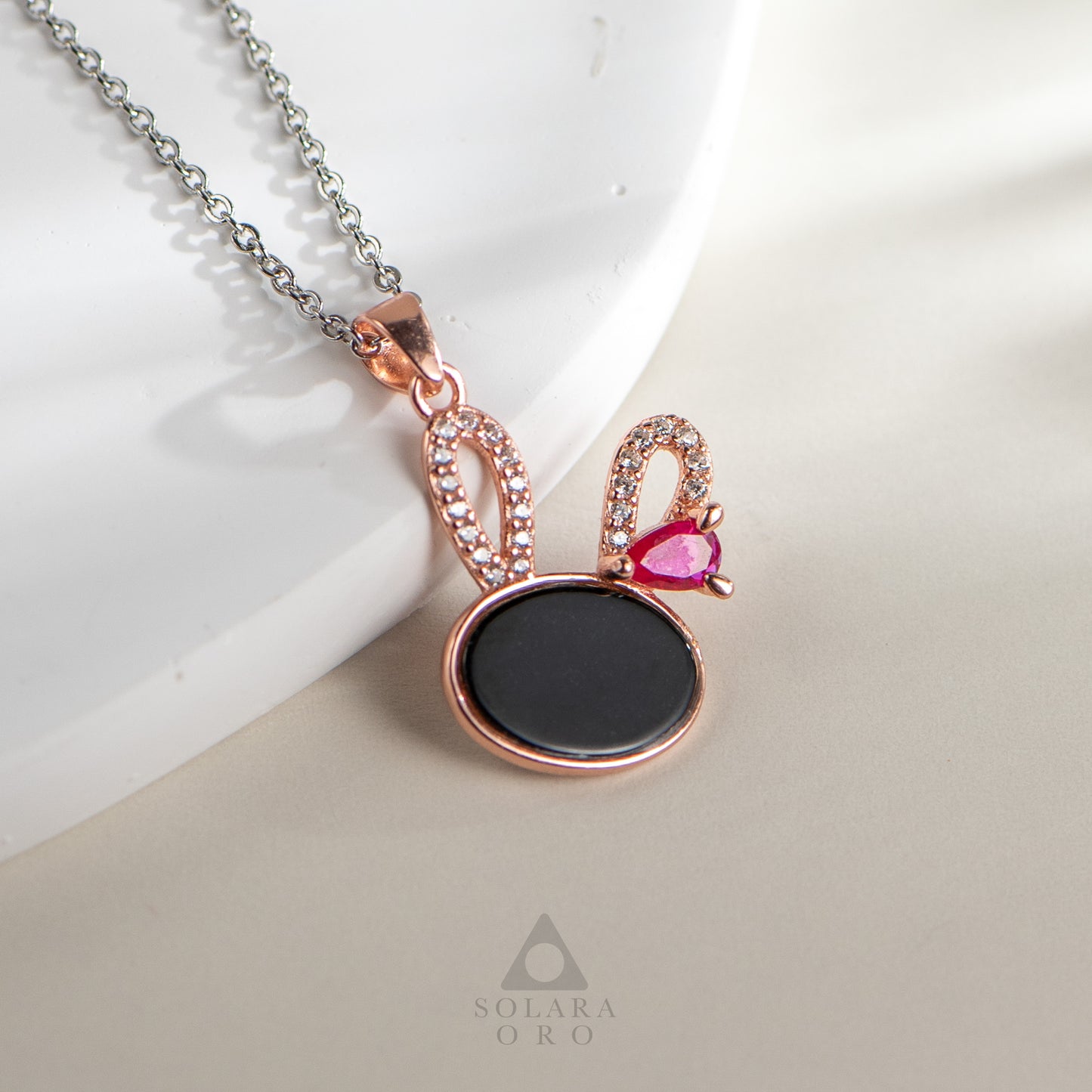 Jewelry necklace with a black pendant and pink gemstone on a white background