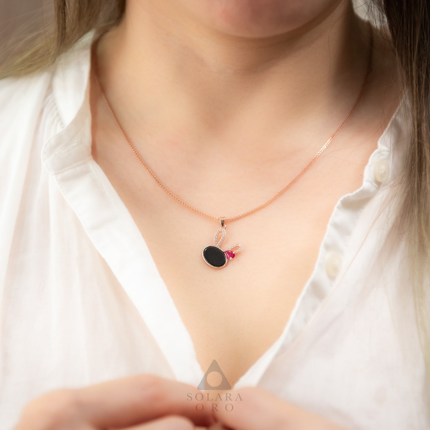 Necklace with a pendant worn by a person, brand 'SOLARA' visible