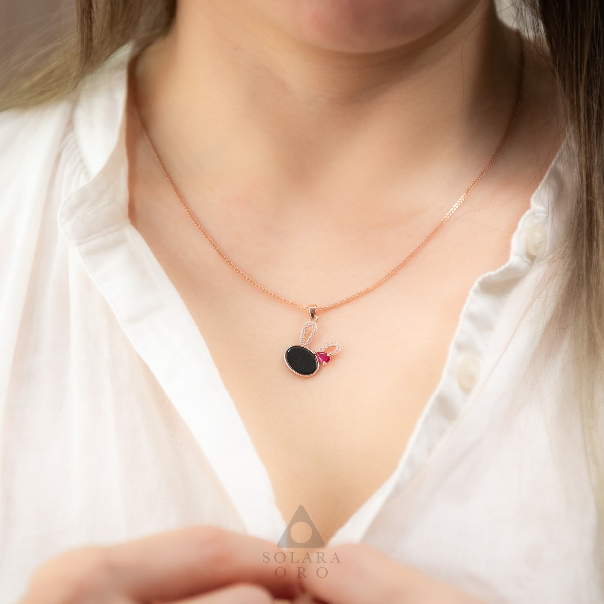 Necklace with a pendant worn by a person, brand 'SOLARA' visible