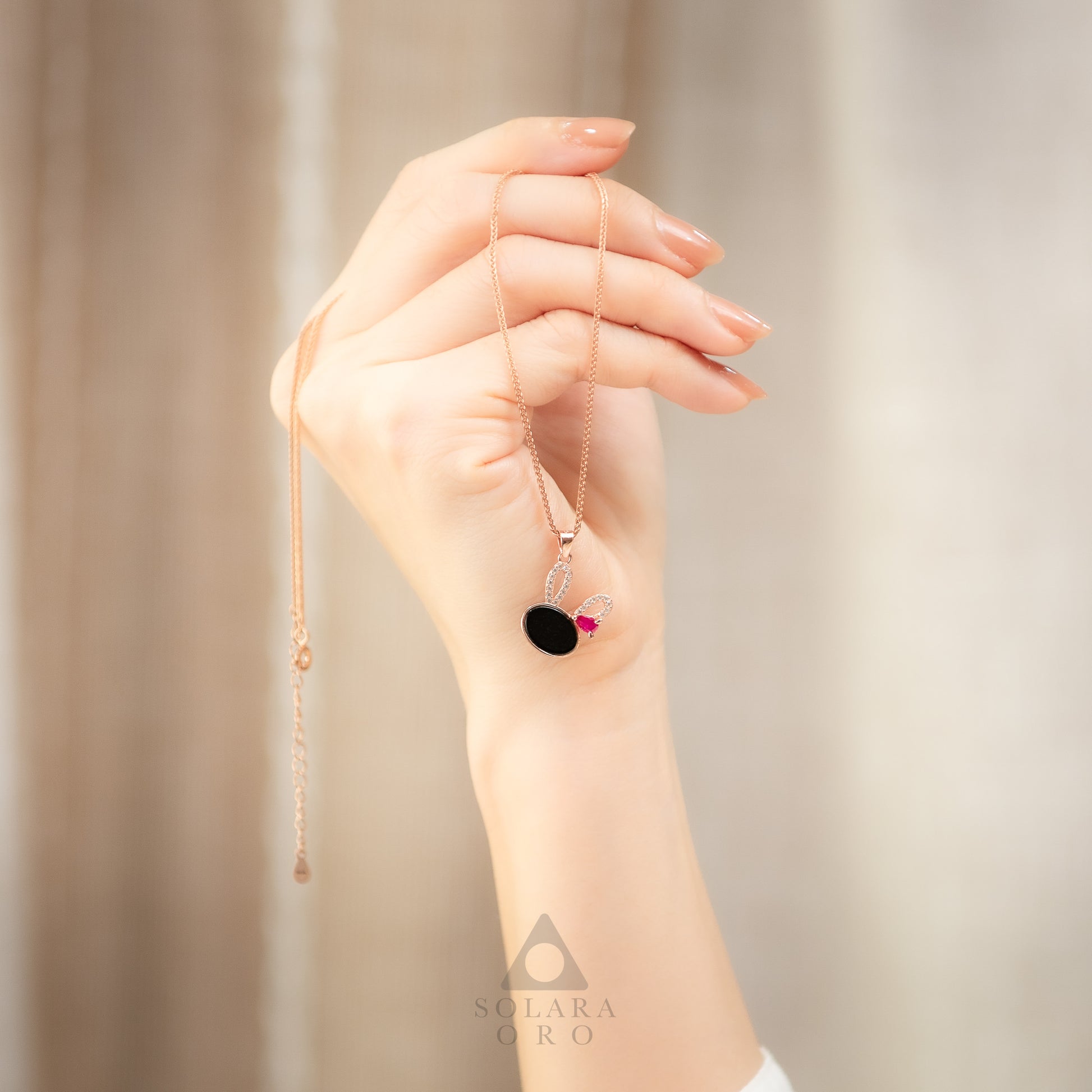 Hand holding a delicate necklace with a blurred background