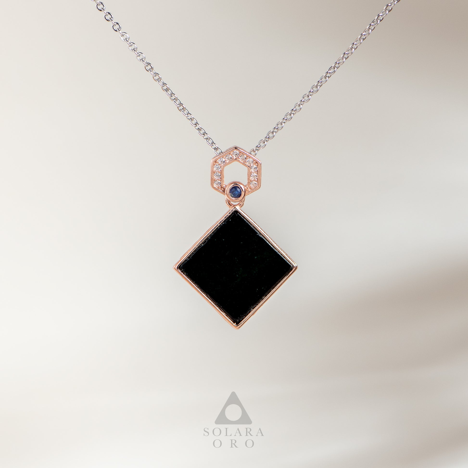 Necklace with a black square pendant and rose gold accents on a light background