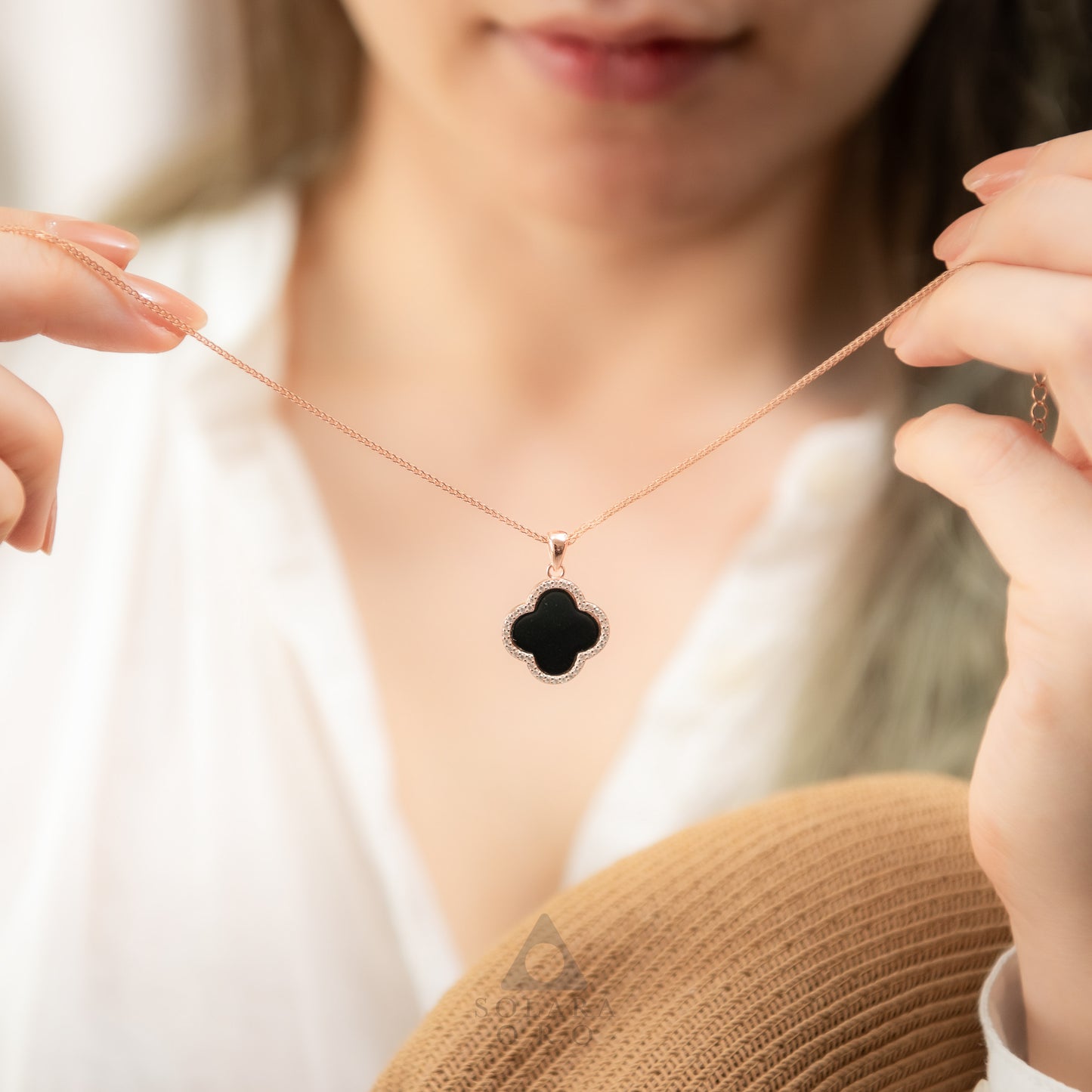 Person wearing a necklace with a black clover pendant