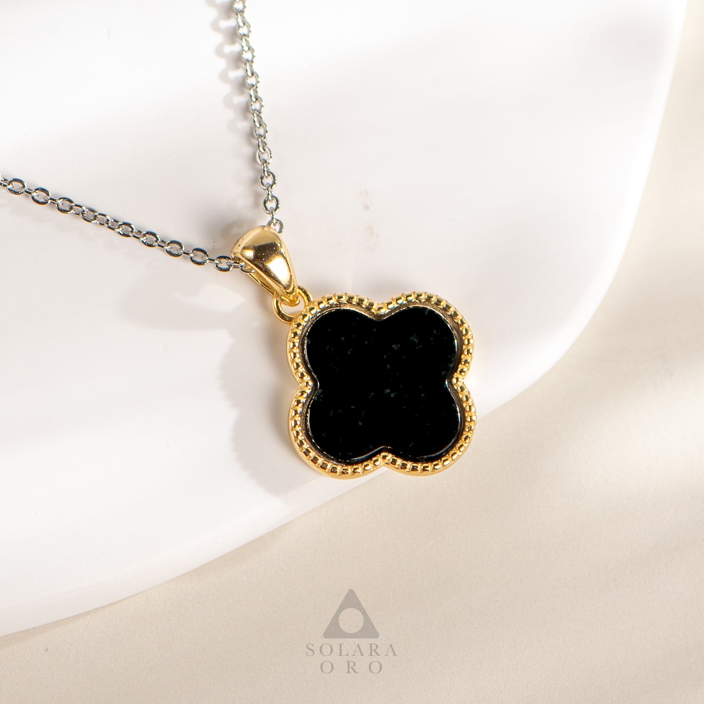Gold necklace with a black pendant on a white background, featuring the brand 'Soleara Oro'.