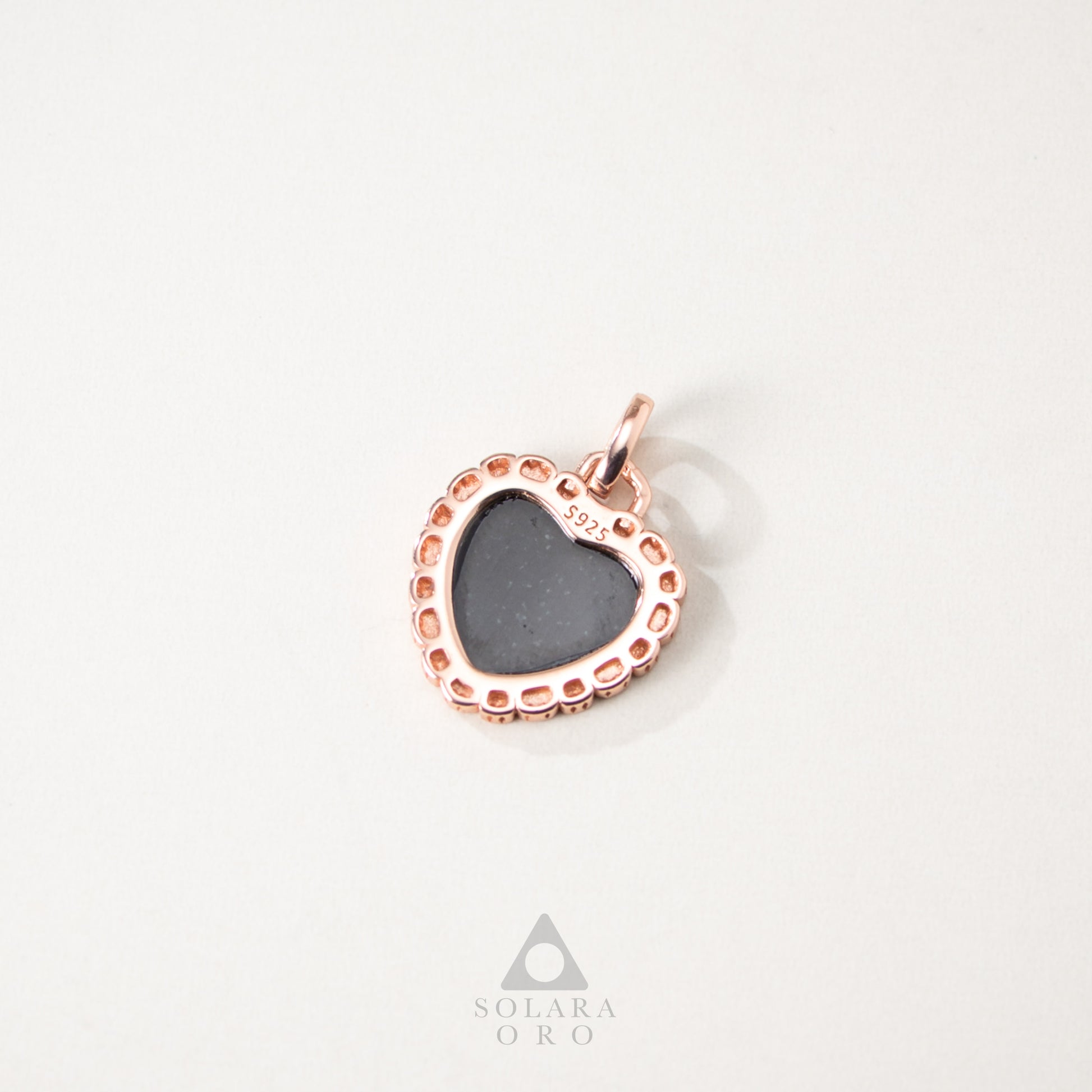 Rose gold pendant with a heart-shaped gray stone on a white background, featuring the Solara Oro logo.