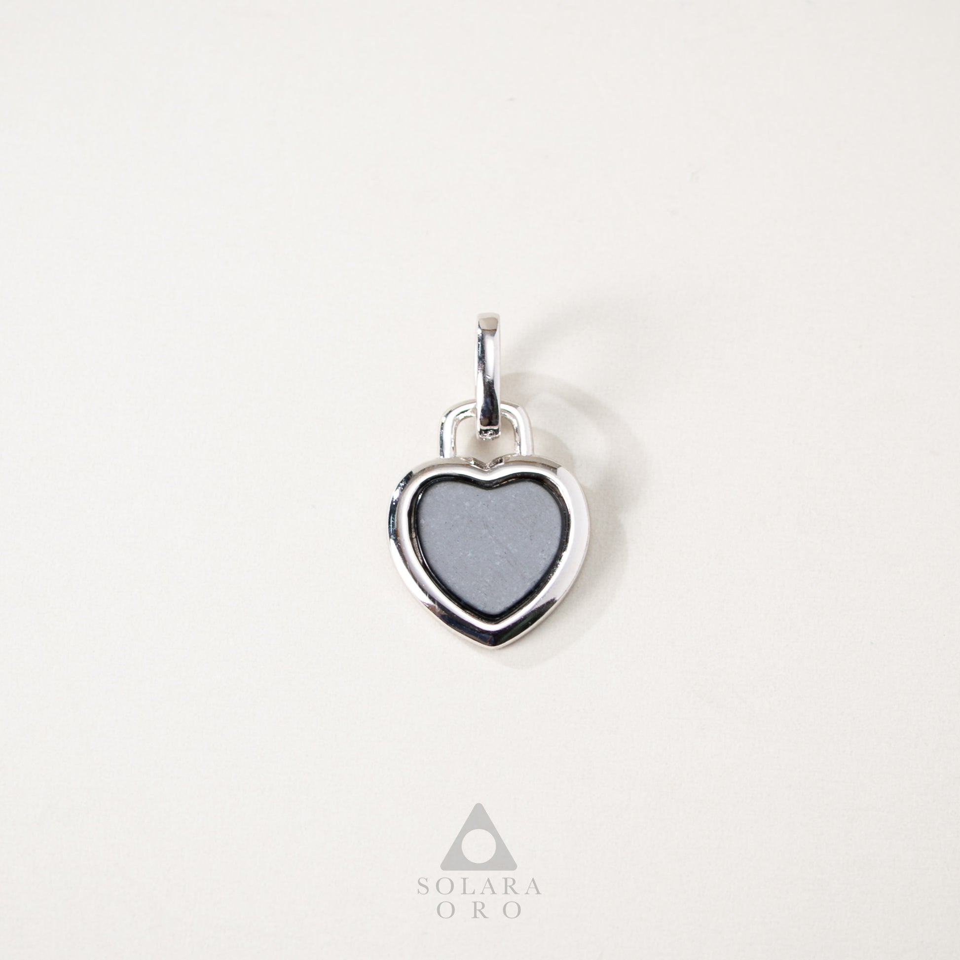 Heart-shaped pendant with gray center on a white background, branded 'Solara Oro'.