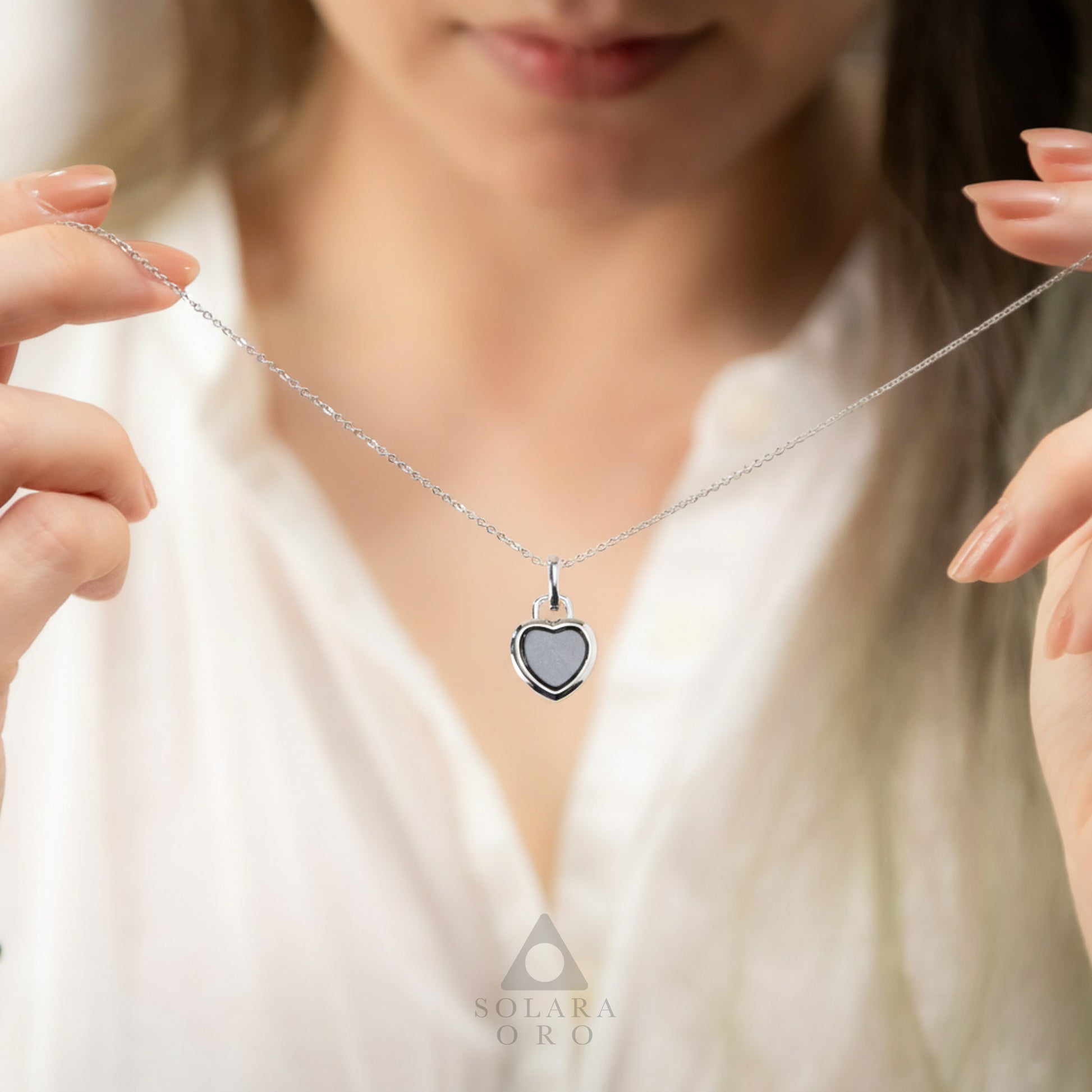 Heart-shaped pendant necklace being held by a person, with 'Solerara Oro' brand visible.