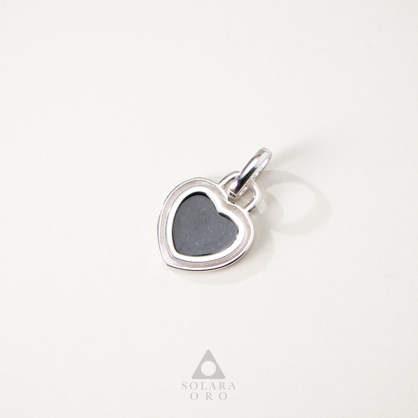 Heart-shaped silver pendant with a gray stone on a white background, featuring the Solara Oro logo.