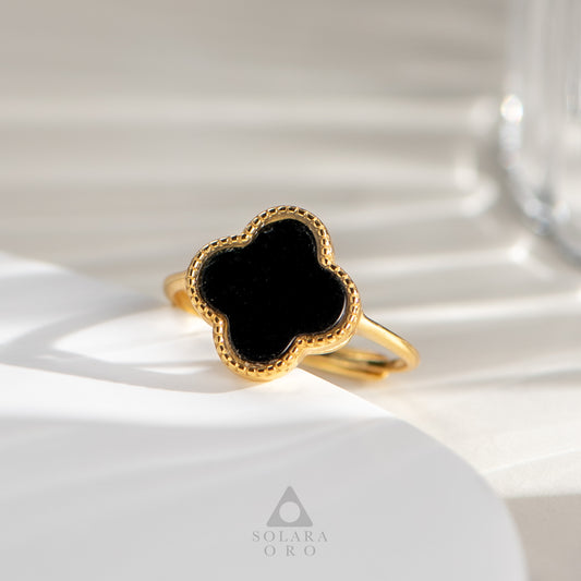 Gold ring with a black stone on a white surface, branded 'Solara Oro'.