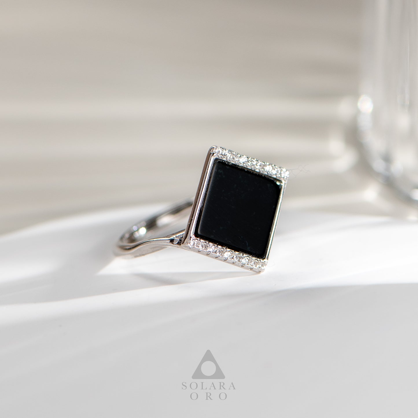 Silver ring with a black gemstone and diamond accents on a white surface, featuring the Solara Oro brand.
