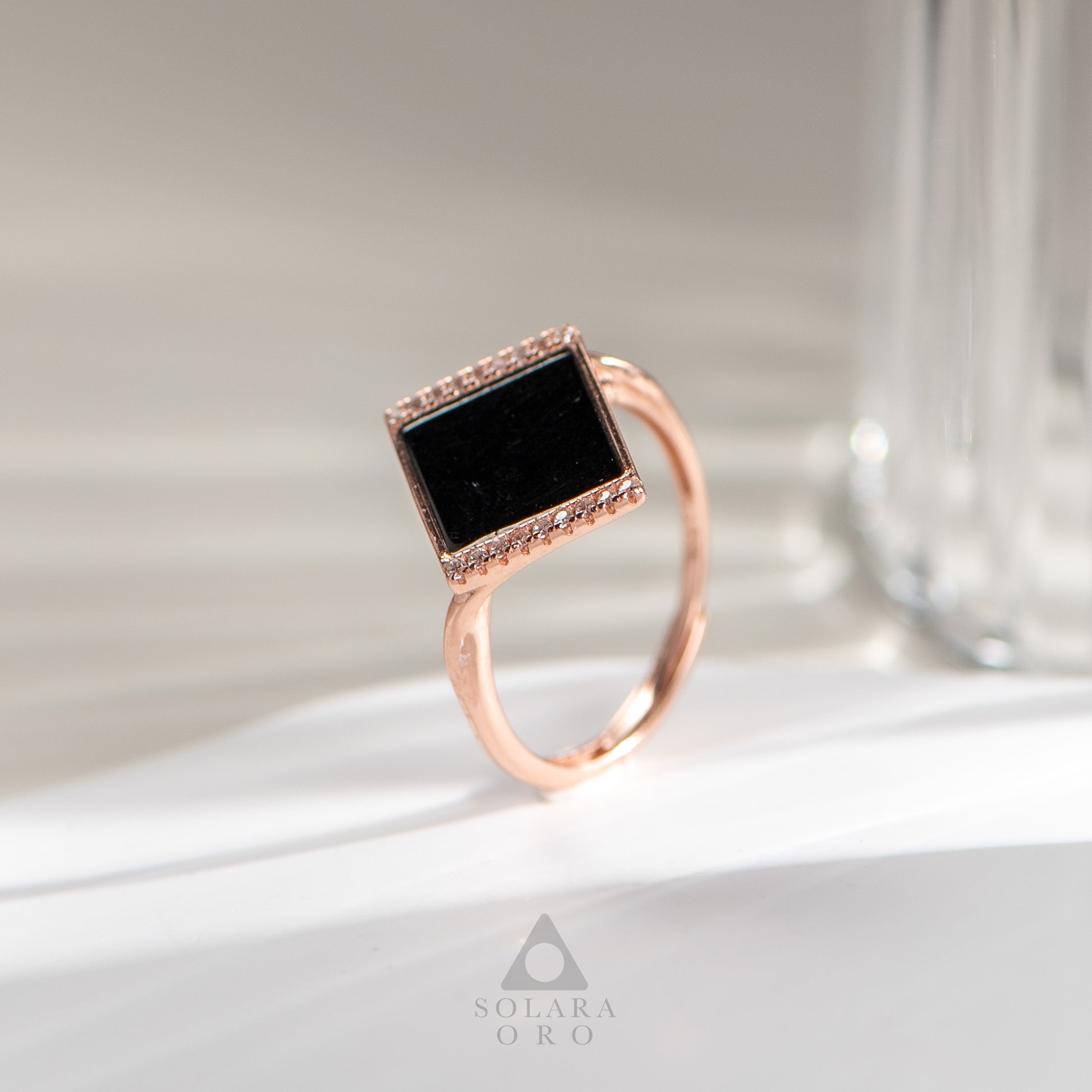 Rose gold ring with a black gemstone on a light background, featuring the Solara Oro brand.