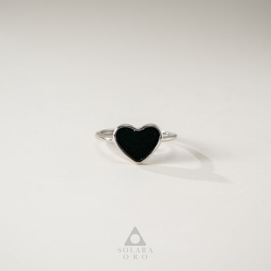 Heart-shaped black stone ring on a light gray background with Solara Oro logo.