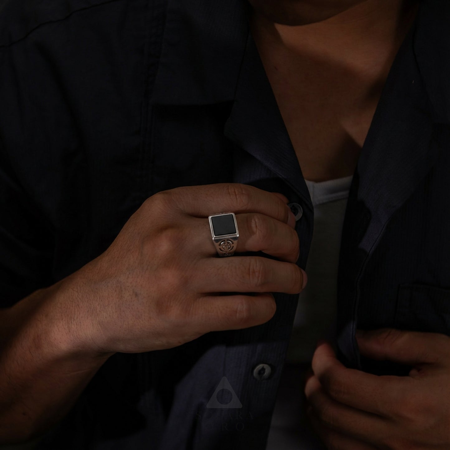 Person wearing a dark shirt with a close-up of their hand adjusting the collar.