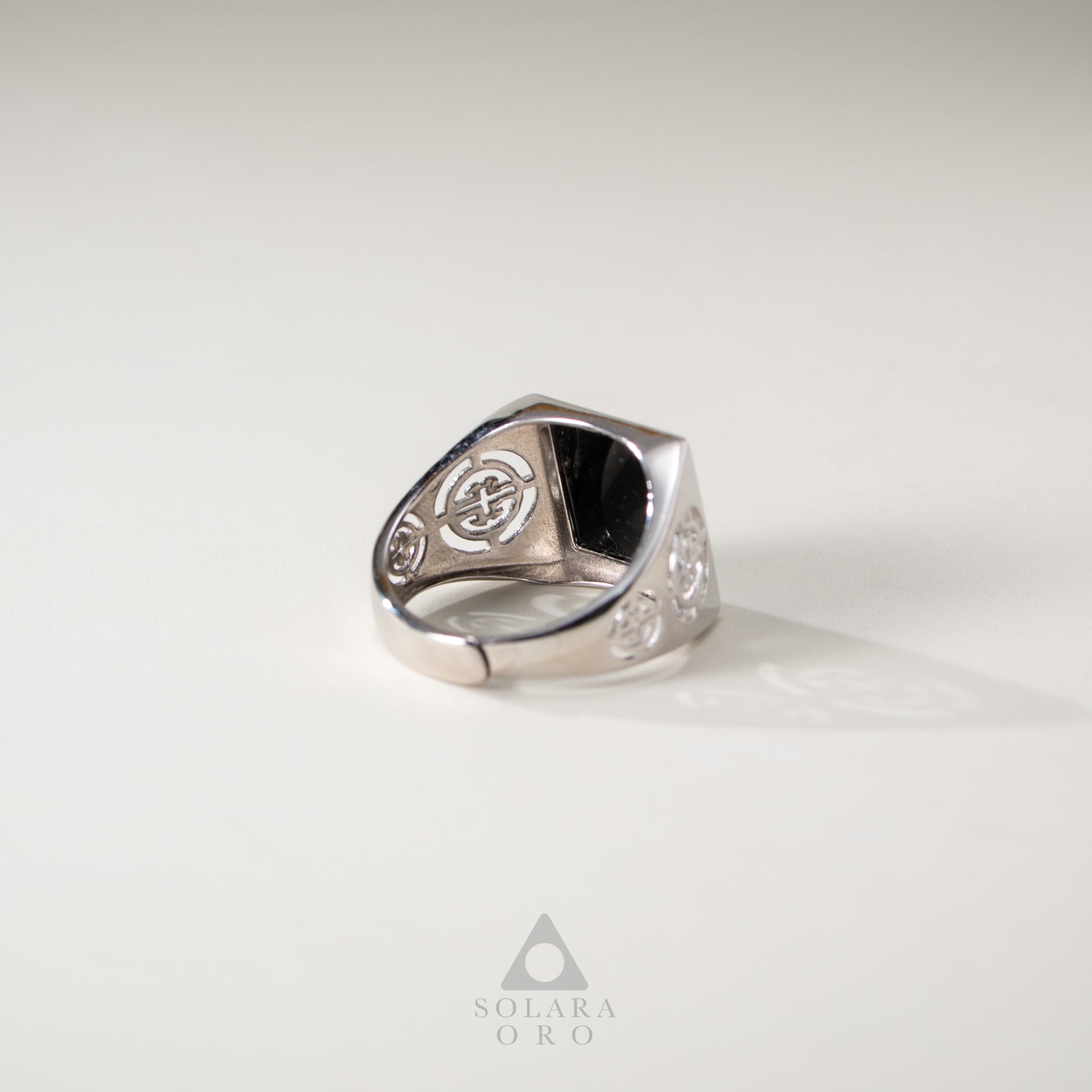 Silver ring with intricate design on a light gray background