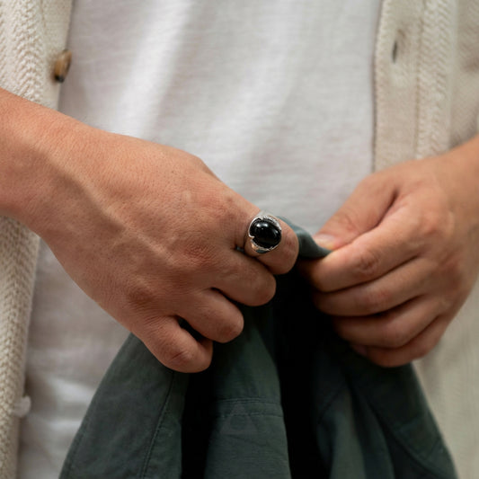 Close-up of hands with a ring holding a green fabric against a neutral background