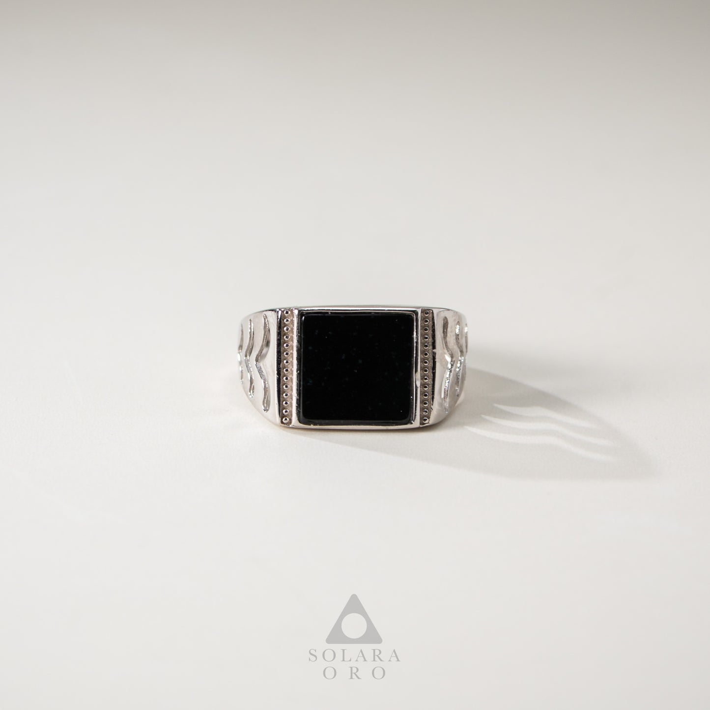 Silver ring with a black stone on a white background, featuring the Solara Oro logo.