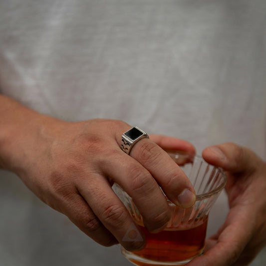Person holding a glass of amber liquid with a plain background
