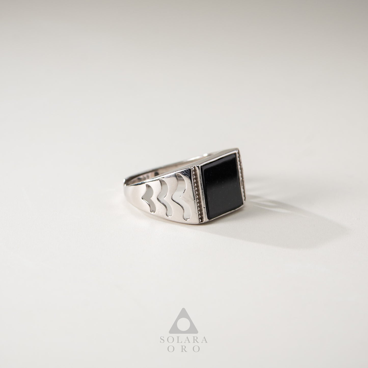 Silver ring with a black stone on a light gray background