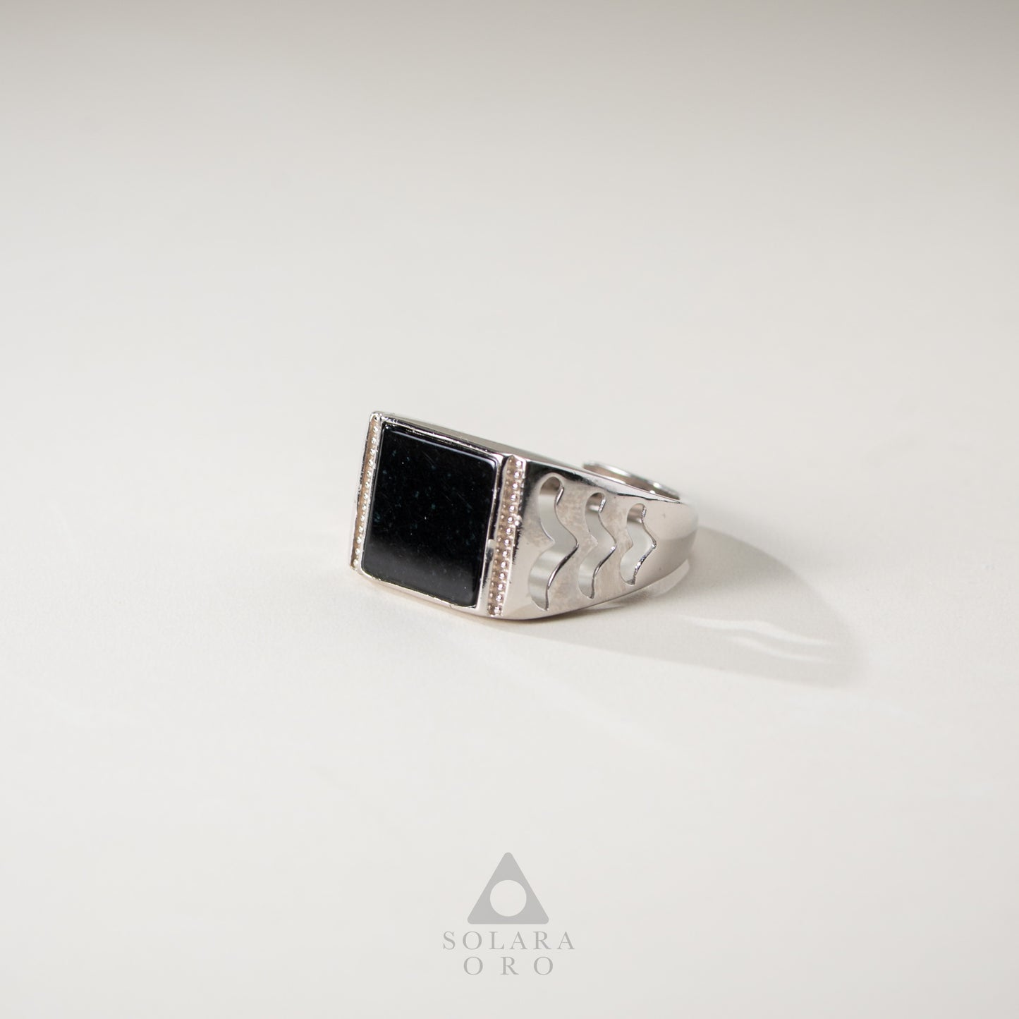 Silver ring with a black stone on a white background, featuring the Solara Oro logo.