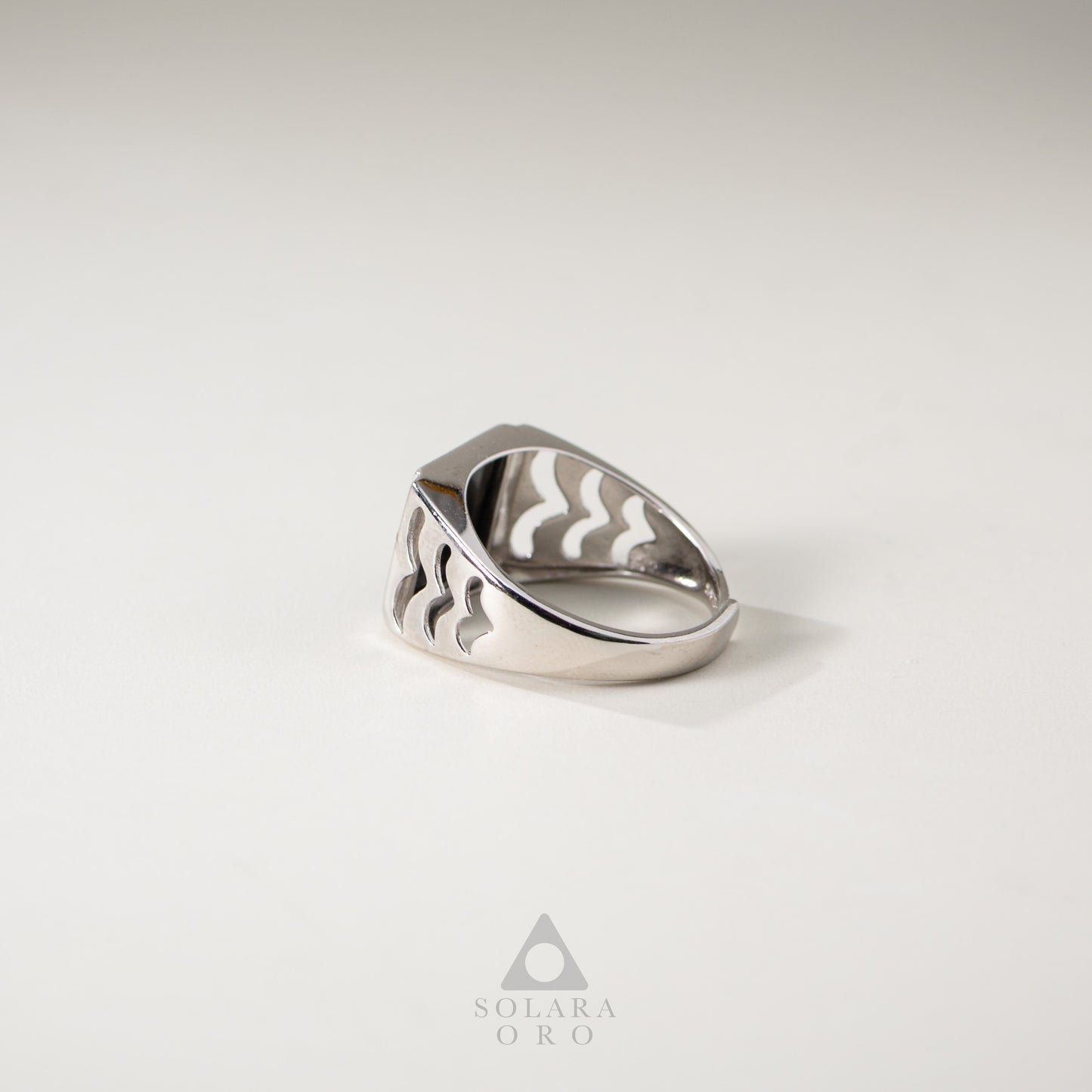 Silver ring with wavy design on a light gray background, featuring the brand 'Solara Oro'.