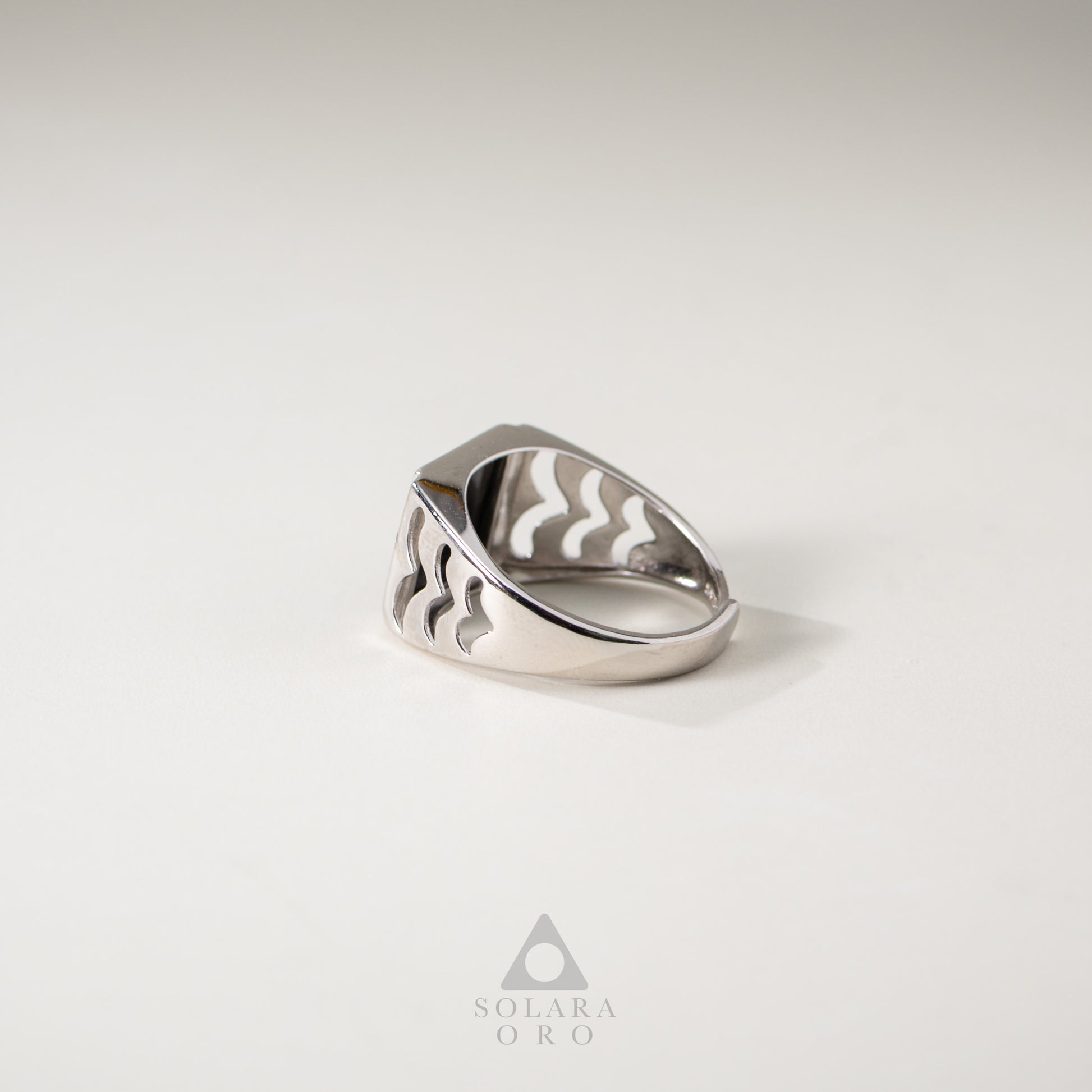 Silver ring with wavy design on a light gray background, featuring the brand 'Solara Oro'.