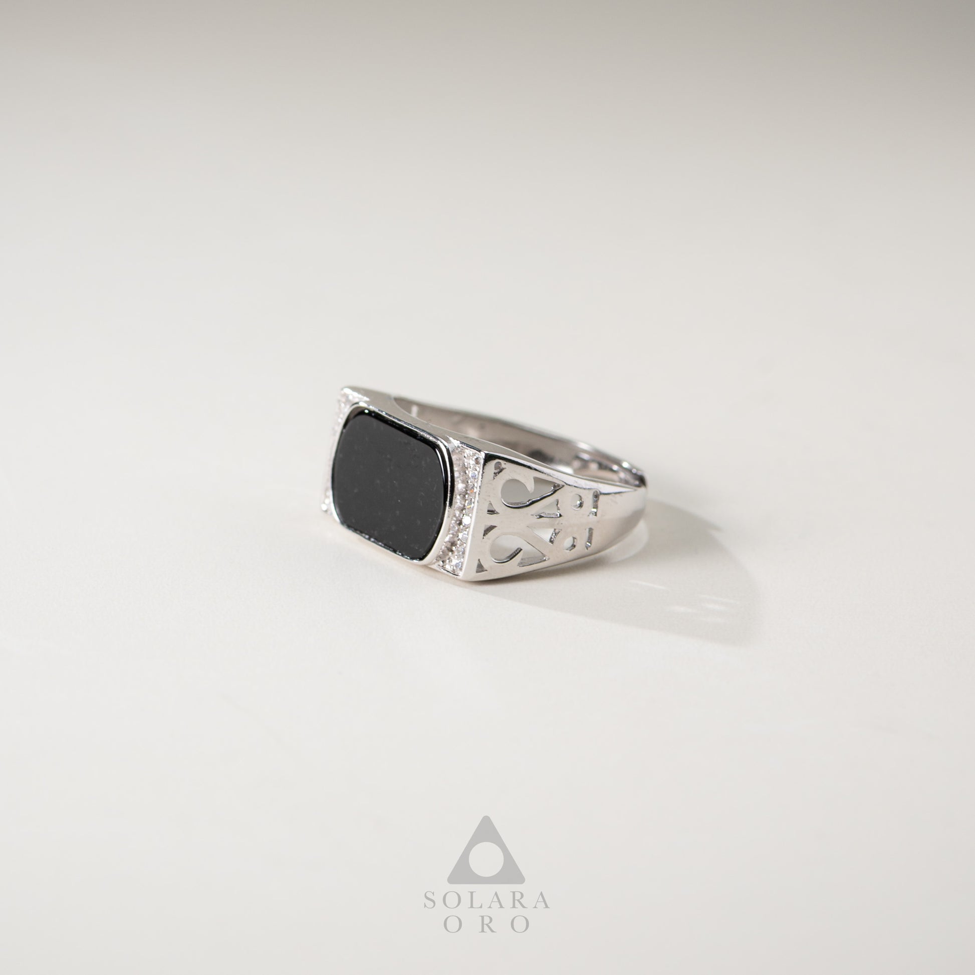 Silver ring with a black stone on a light gray background, branded 'Soleara Oro'.