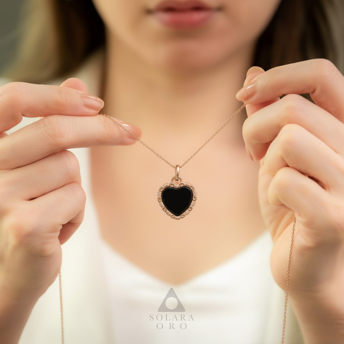 Heart-shaped necklace with a black stone held by hands, brand 'Solerara Oro' visible.