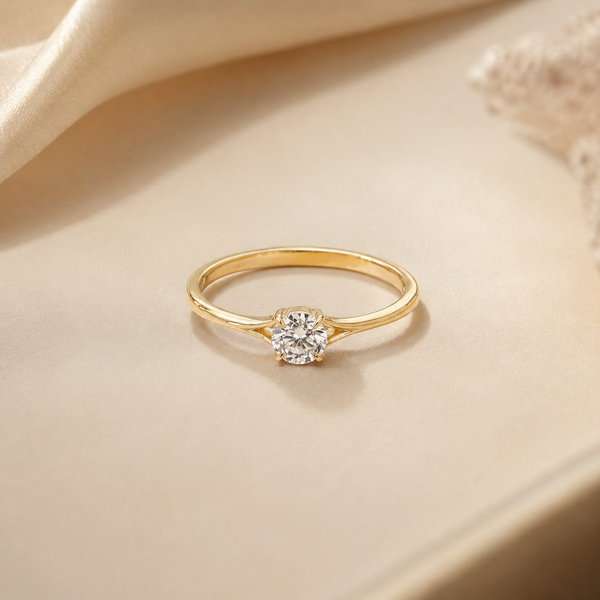 Yellow gold round solitaire diamond ring with a split shank, front view on a beige background