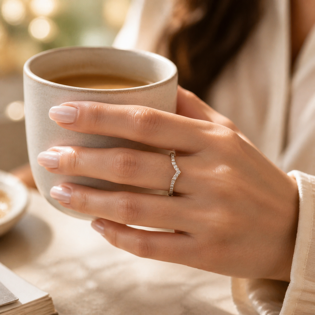 Kairos pavé diamond chevron ring worn on hand, holding a coffee cup