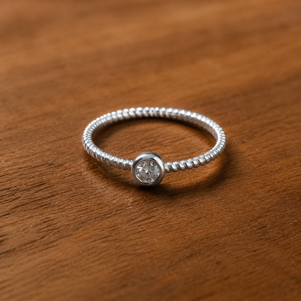 The Majestic Jewel ring on a wood surface, round bezel-set diamond on a twisted rope band
