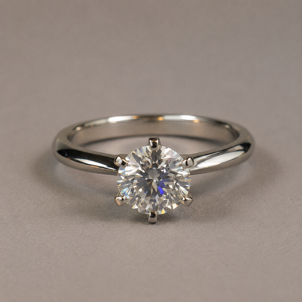 The Eternal Vow ring, a round brilliant-cut diamond solitaire in a six-prong setting, on a neutral gray background