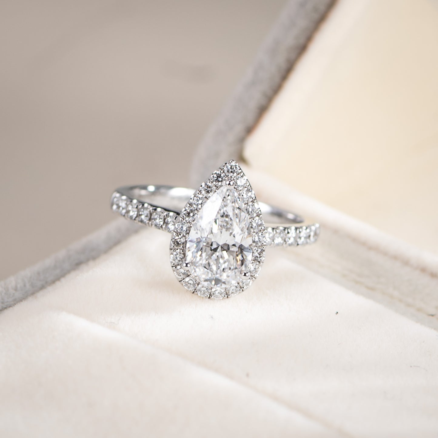 Diamond ring with a pear-shaped center stone on a soft fabric background