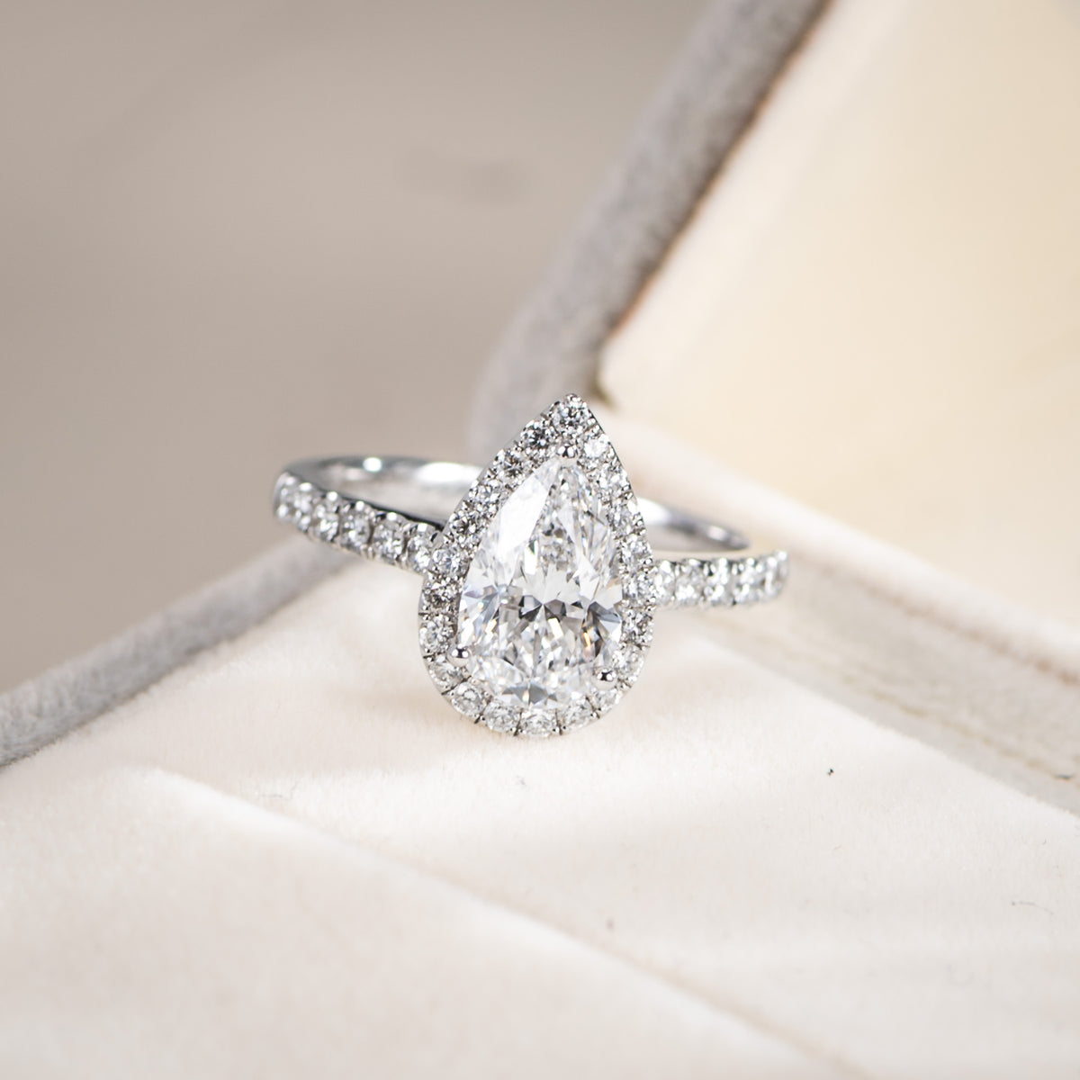 Diamond ring with a pear-shaped center stone on a soft fabric background