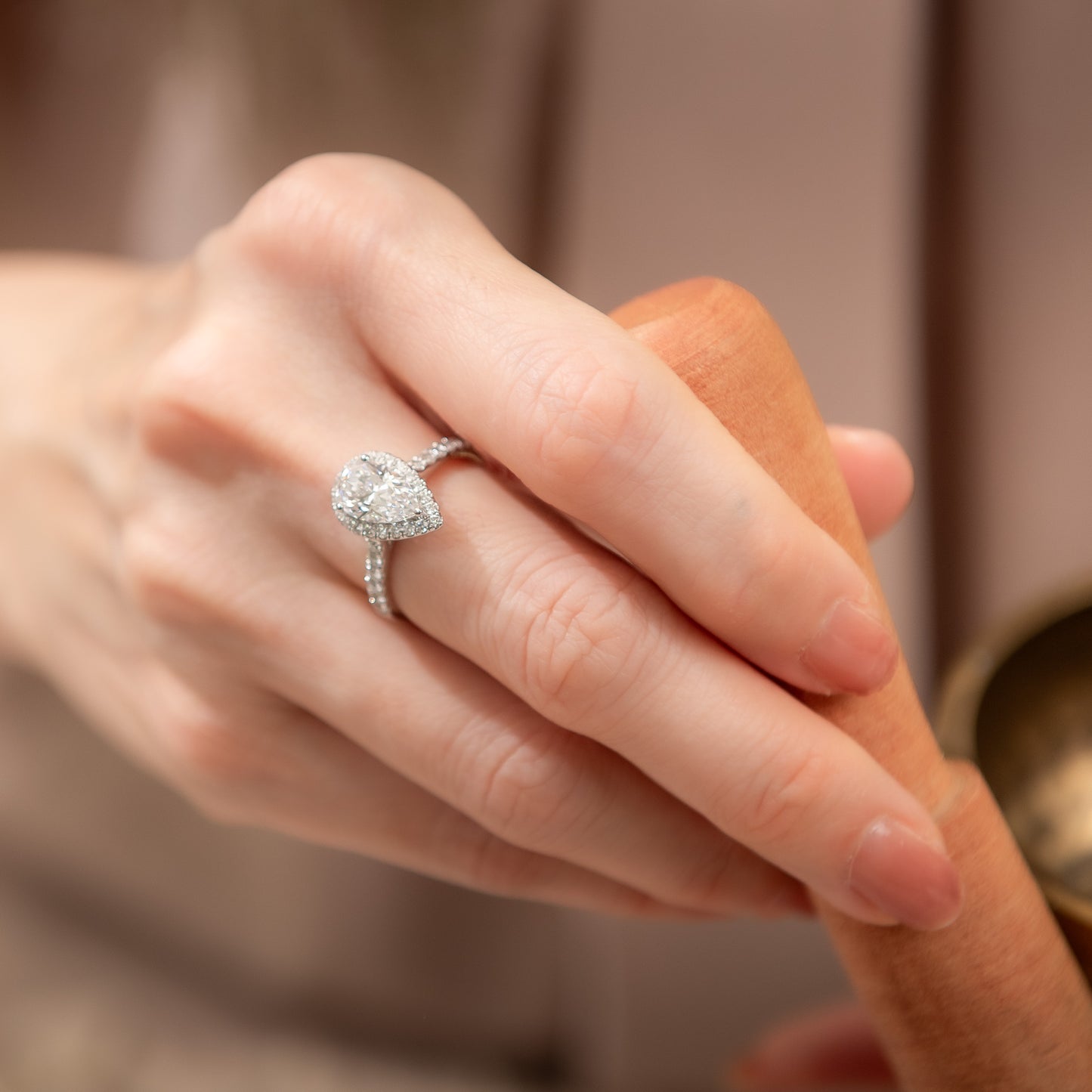 Close-up of a hand wearing a diamond ring with a blurred background