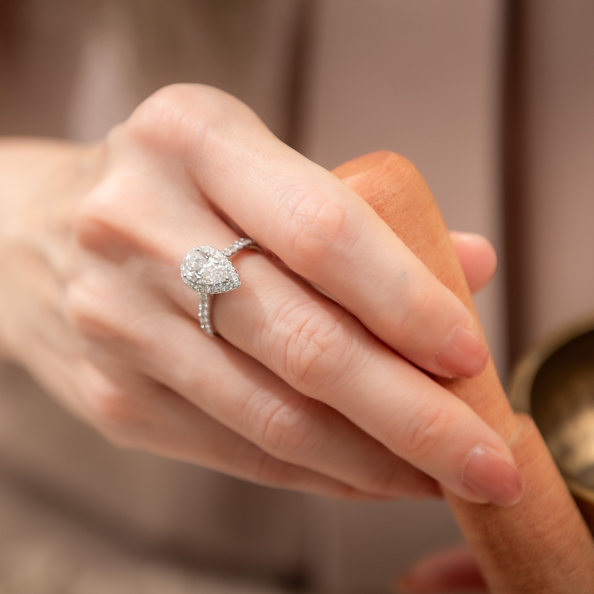 Close-up of a hand wearing a diamond ring with a blurred background