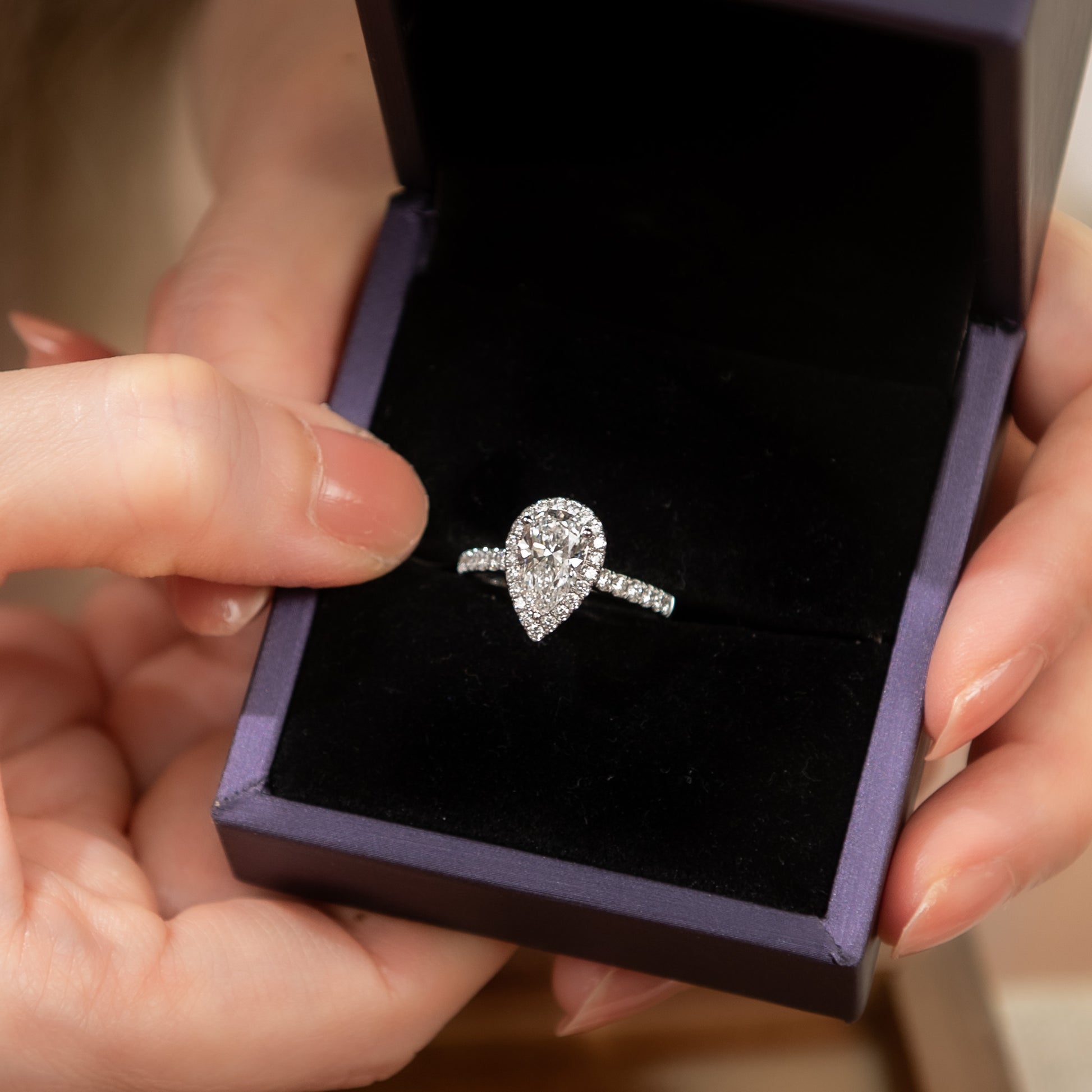 Diamond ring in a purple box held by hands