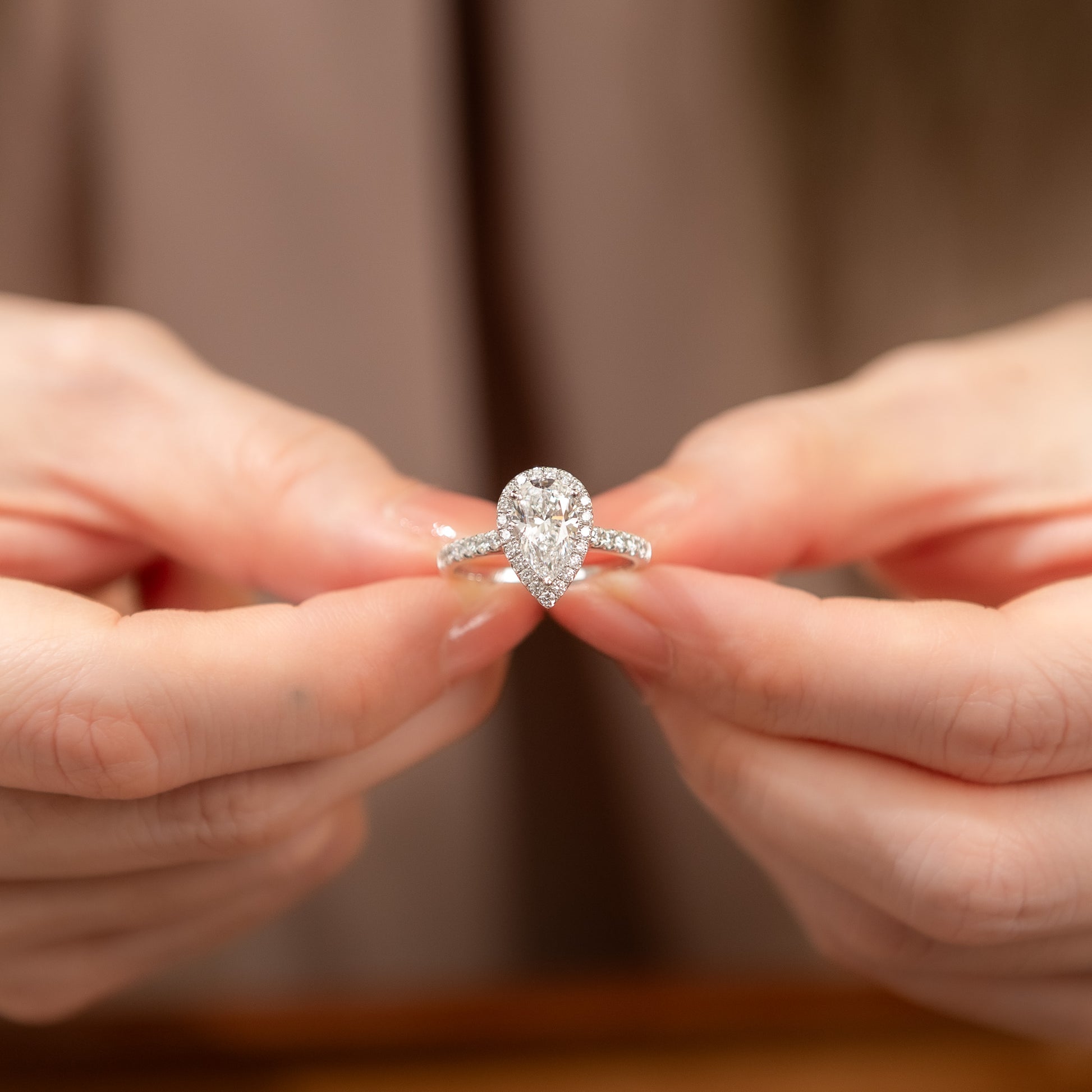 Person holding a diamond ring with a blurred background