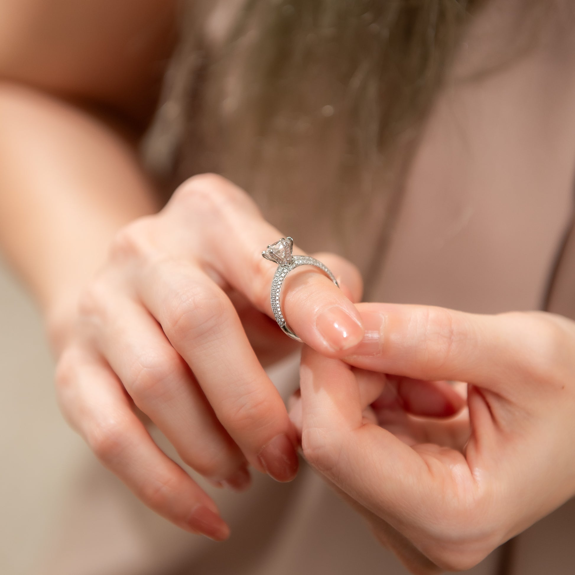 Close-up of a hand wearing a diamond ring with a blurred background
