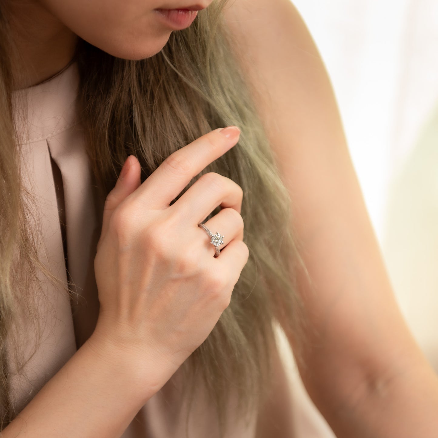 Close-up of a person wearing a diamond ring on a blurred background