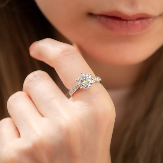 Close-up of a hand wearing a diamond ring with a blurred background