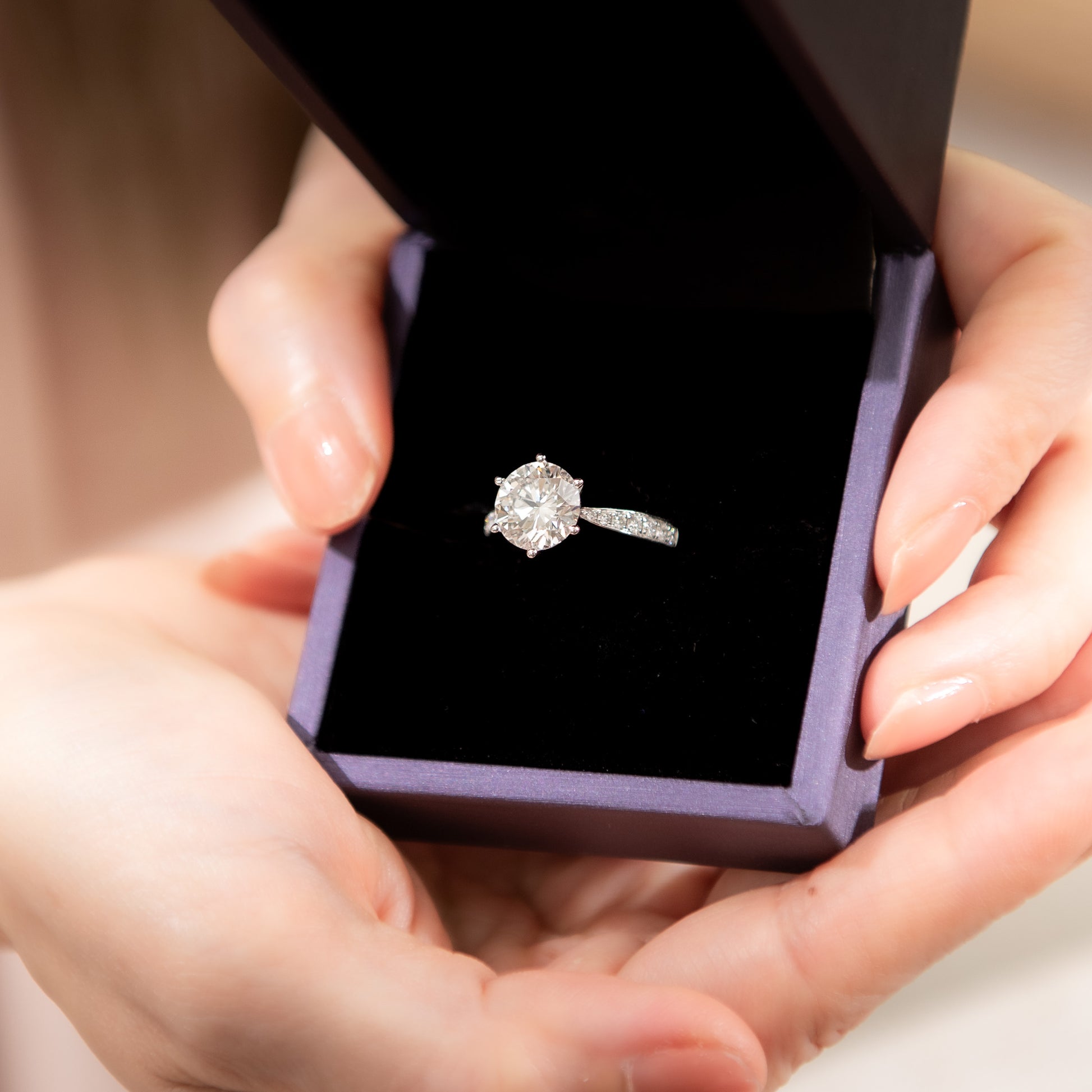 Diamond ring in a purple box held by hands