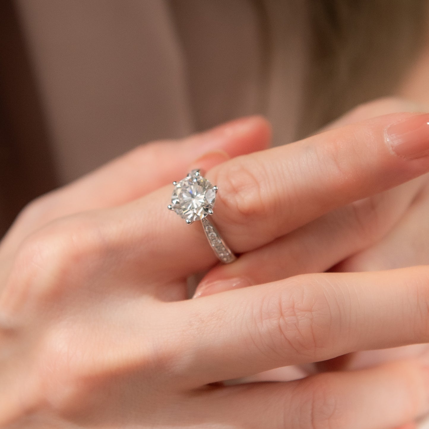 Close-up of a hand wearing a diamond ring with a blurred background