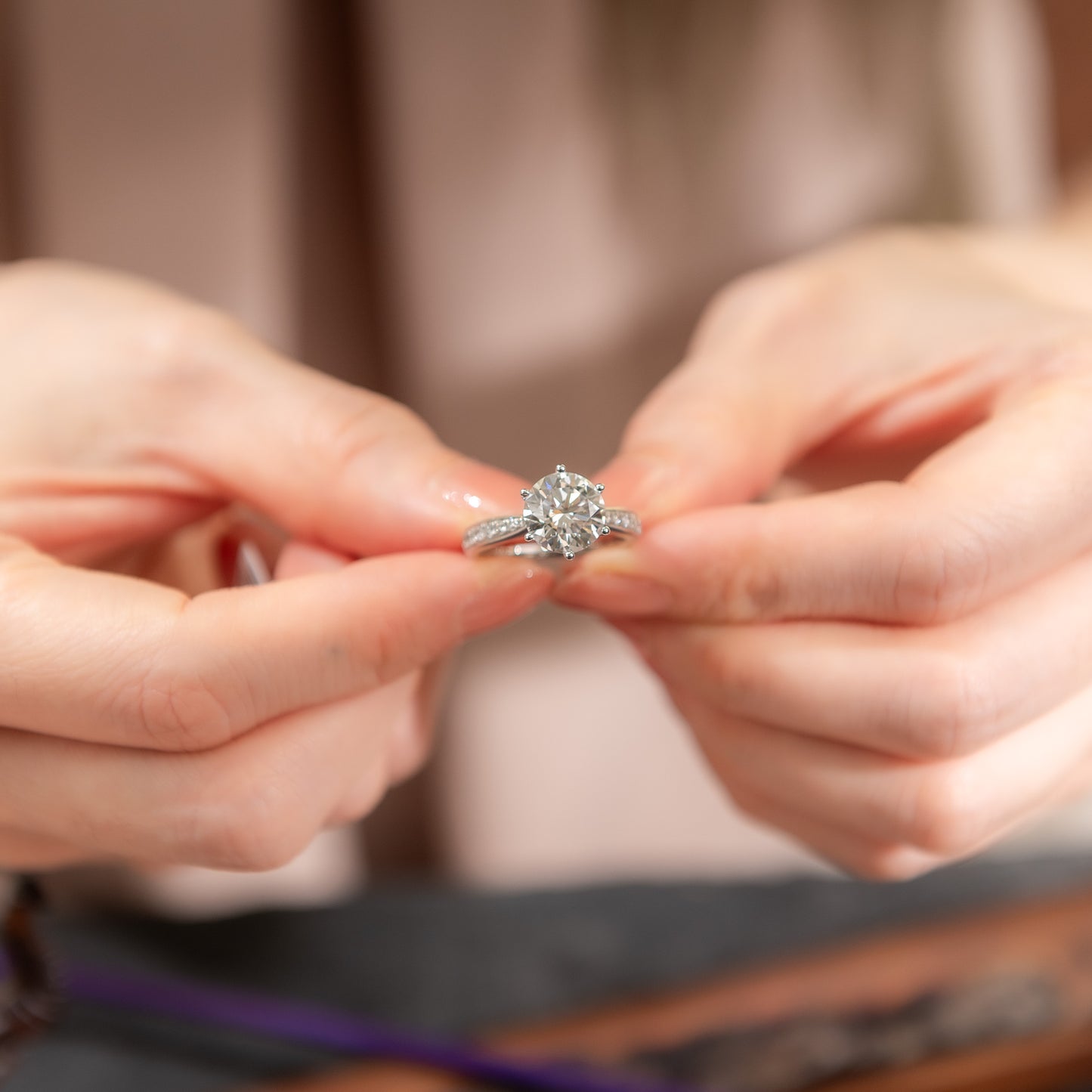 Close-up of hands holding a diamond ring with a blurred background
